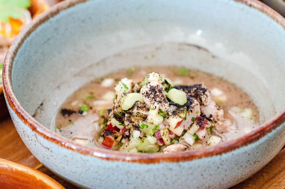 Artfully plated seafood dish in ceramic bowl with garnish and spices