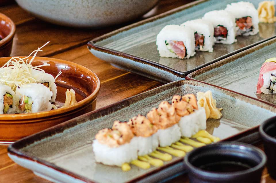 Assorted sushi rolls and nigiri on slate plates with soy sauce and garnishes