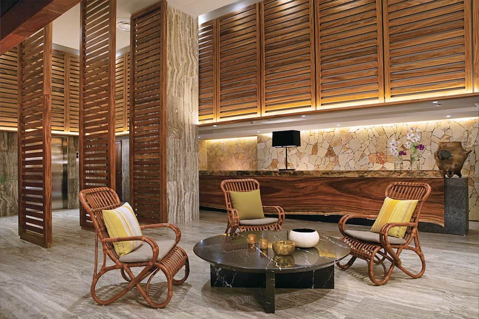 Luxury lobby lounge with wooden shutters, rattan chairs, and black marble table