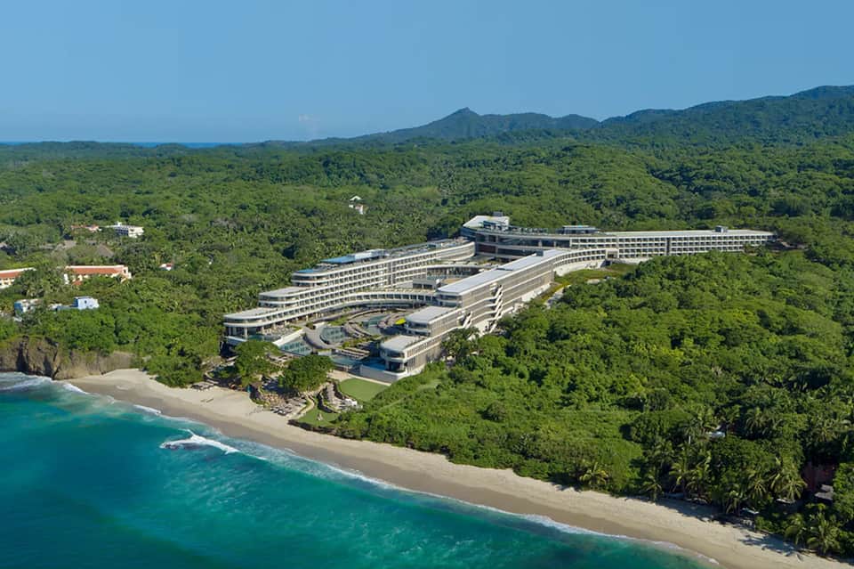 Modern beachfront resort nestled in lush jungle overlooking turquoise ocean waters