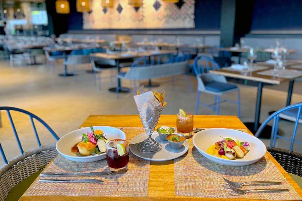 Fine dining restaurant table set with plated dishes, beverages, and artistic tableware in elegant modern interior