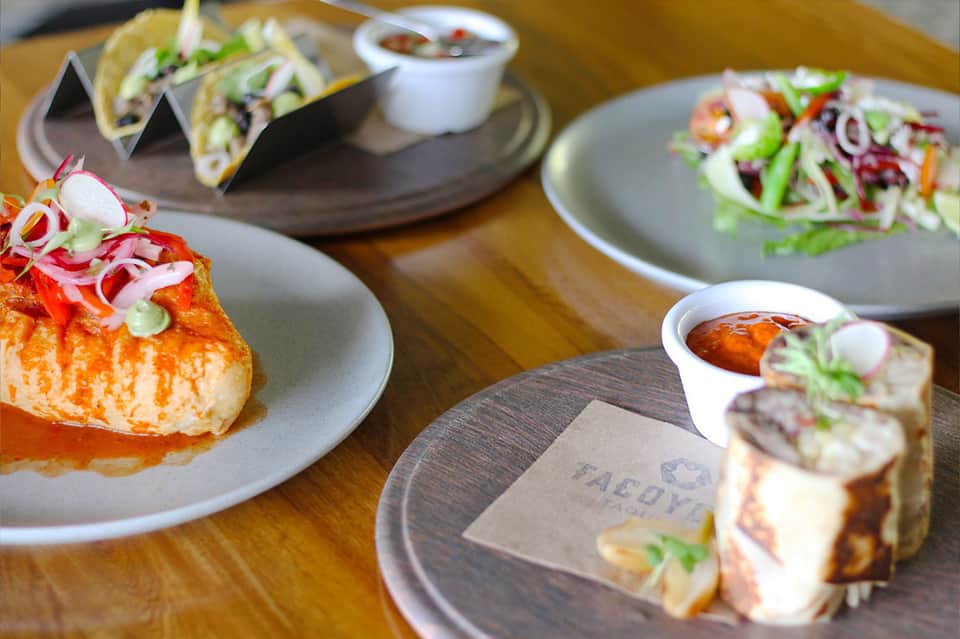 Gourmet Mexican cuisine dishes including tacos and ceviche appetizers on wooden table at resort restaurant