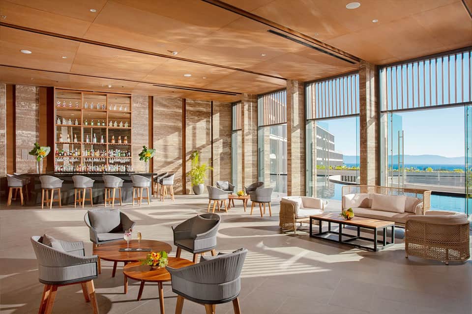 Luxury lounge with wooden ceiling, bar, fireplace, ocean views, and contemporary furnishings