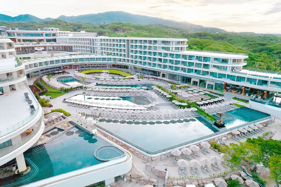Luxury resort aerial view with multiple pools, hot springs, and mountainous landscape