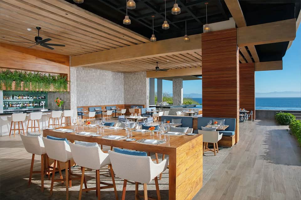 Upscale oceanview restaurant with wooden beams, bar seating, and ocean horizon views