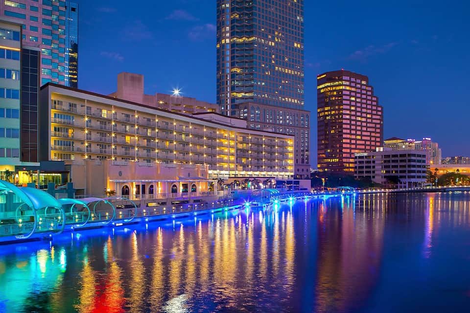 Waterfront hotel complex at dusk with blue LED lighting reflected in calm water
