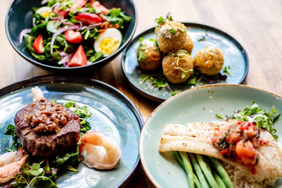 Gourmet plated dishes including salad, fish, beef, and appetizers on ceramic plates