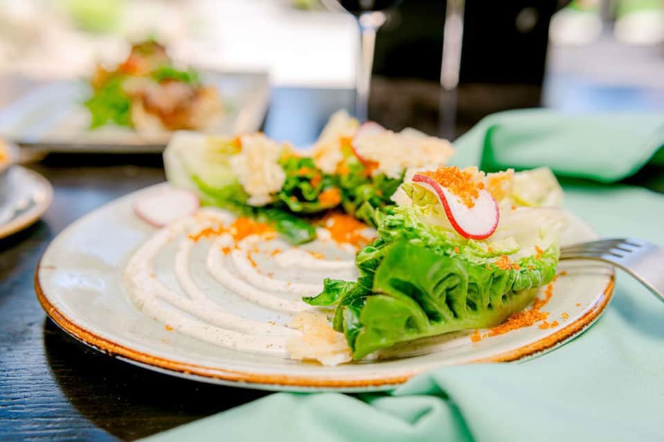 Gourmet plated dish with white sauce, greens, and orange roe garnish at resort restaurant