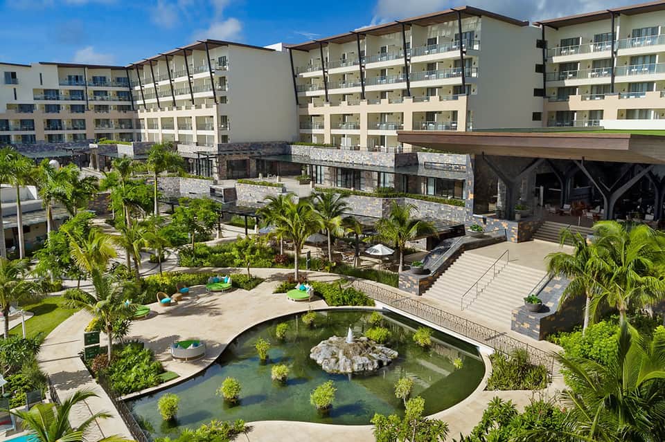 Modern resort courtyard with multi-story white apartments, palm trees, and koi pond