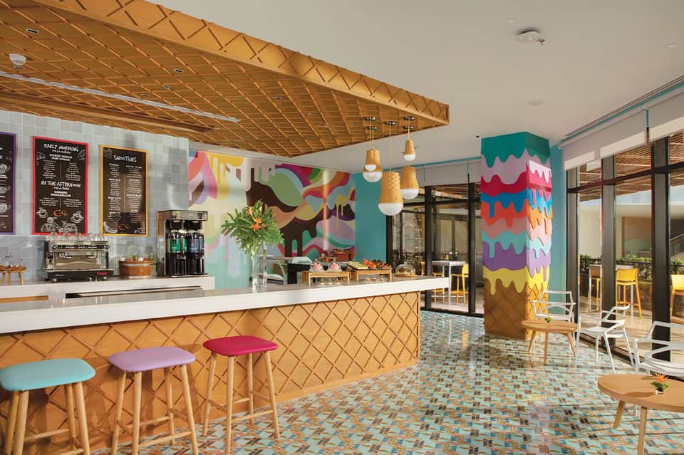 Vibrant casual dining area with colorful wall art, wooden ceiling, and tropical bar seating