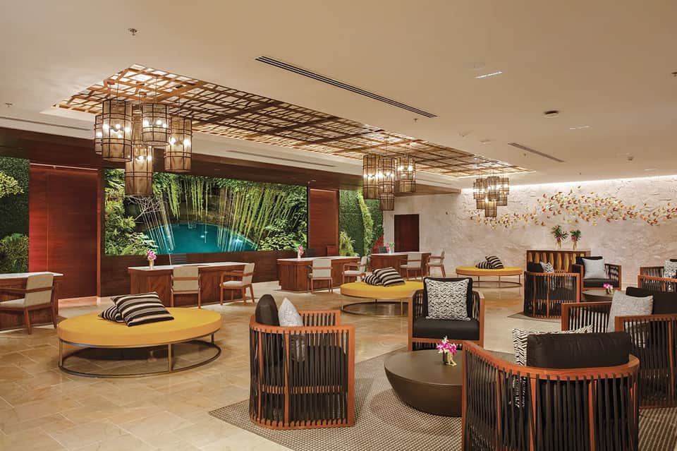 Contemporary lounge with tropical wall mural, colorful round tables, and artistic lighting