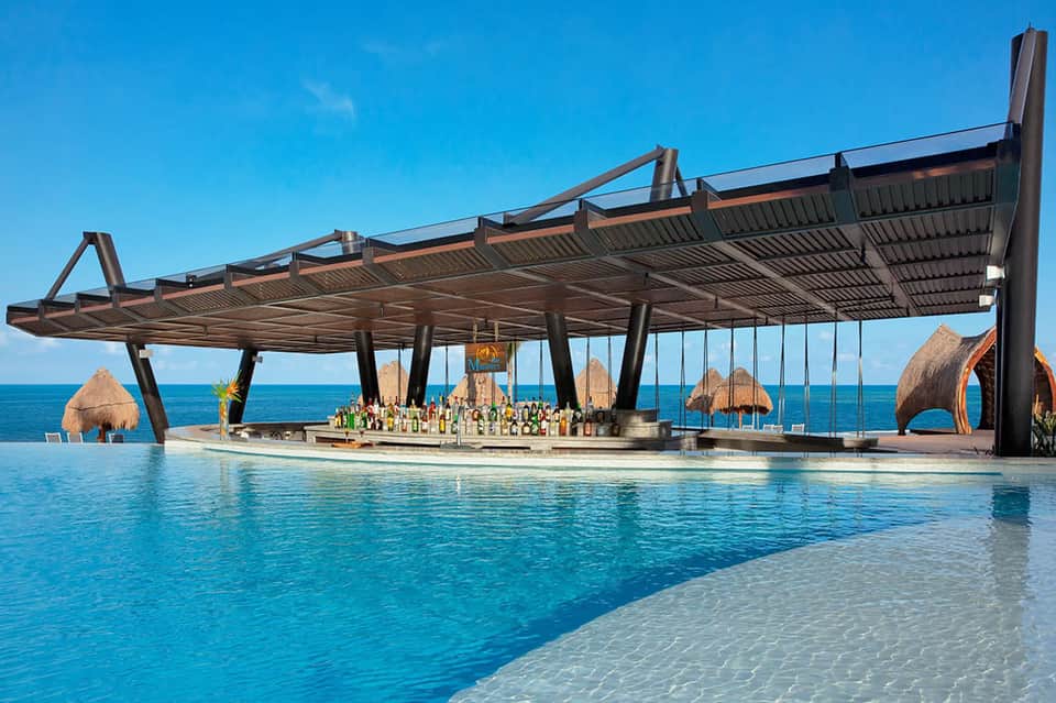 Luxury resort pool bar with geometric structure overlooking turquoise ocean