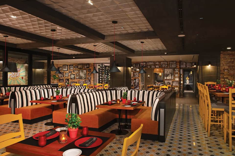 Vibrant restaurant interior with striped seating, orange accents, and photo-covered walls