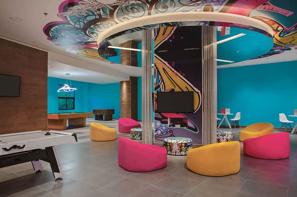 Colorful kids' recreation room with turquoise walls, pink and orange bean bag chairs, and game tables