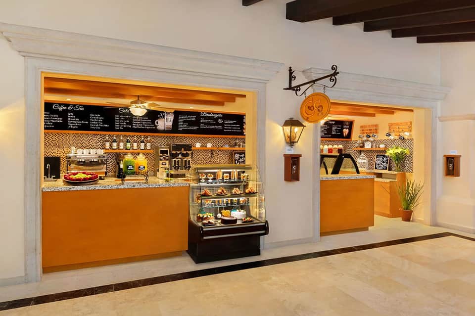 Bright café and coffee shop interior with orange and black design, display cases, and counter seating