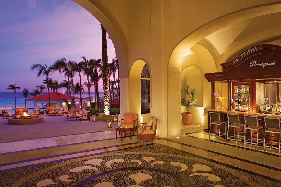 Elegant archway bar and lounge overlooking beach at dusk with decorative floor tiles