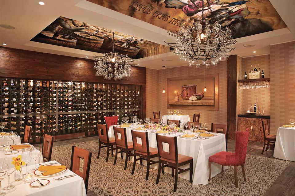 Fine dining wine cellar room with crystal chandeliers and white tablecloth tables