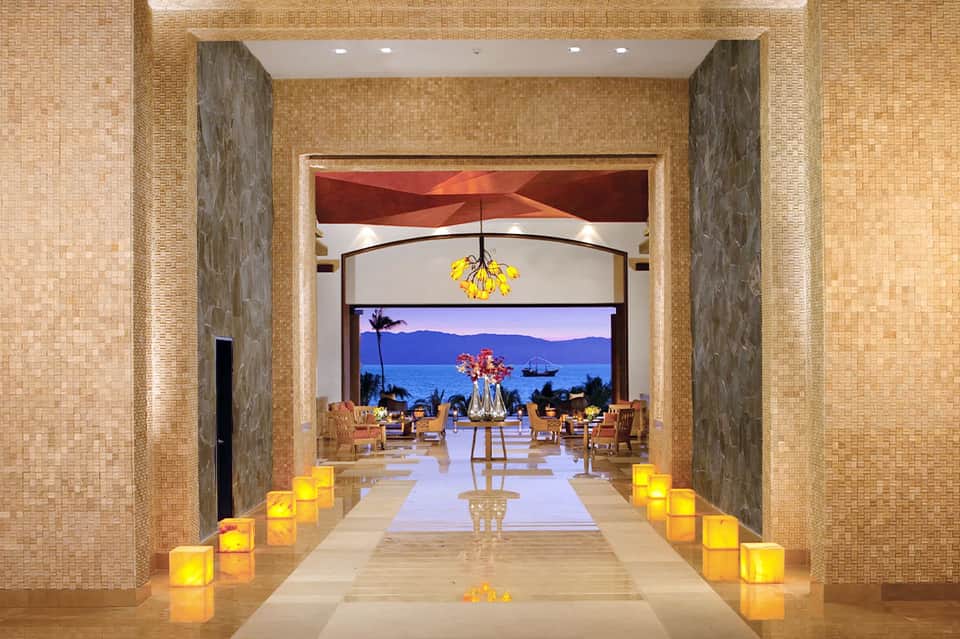Elegant spa entrance with candlelit pathway, ocean view, and contemporary interior design