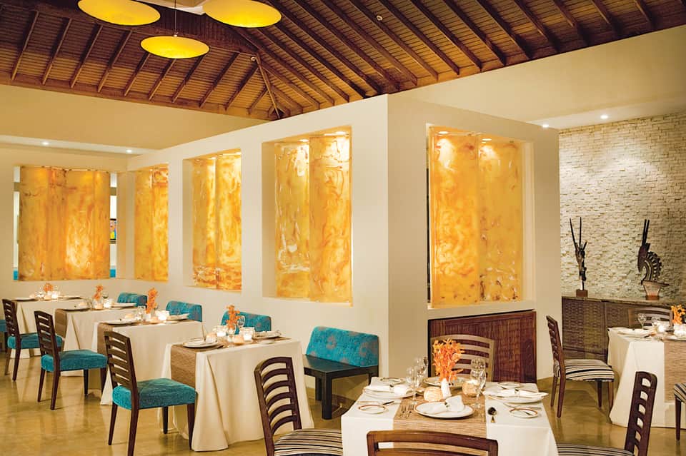 Elegant fine dining restaurant with yellow artwork and turquoise chair accents