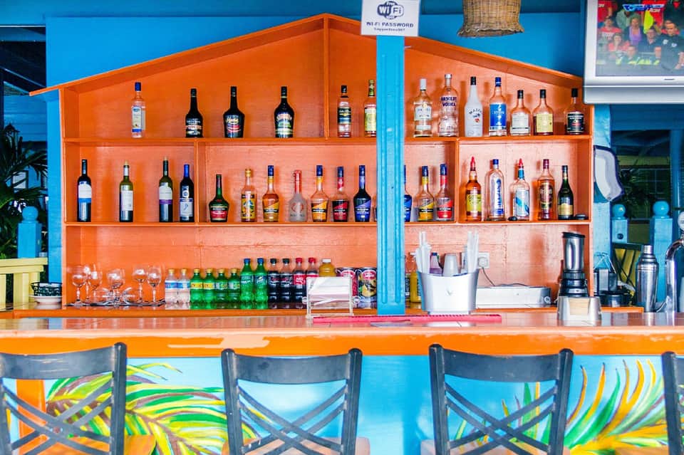 Colorful beachfront bar with orange shelving, vibrant seating, and WiFi access