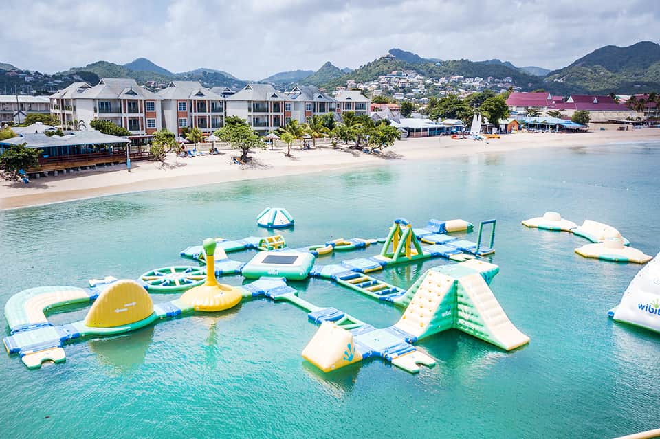 Inflatable water park with various floating obstacles and slides in turquoise shallow water