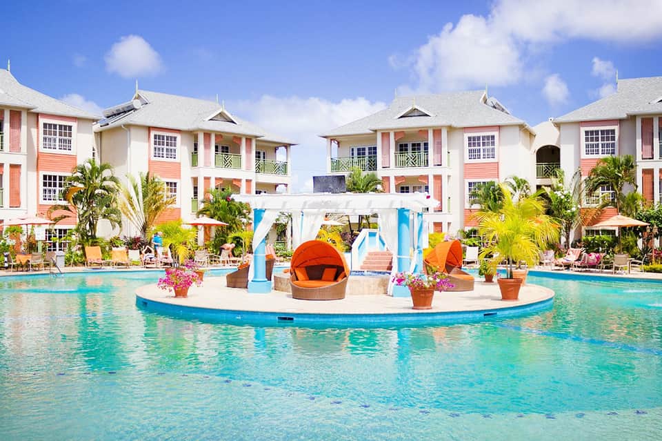 Colorful resort buildings with turquoise pool and central island cabana structure