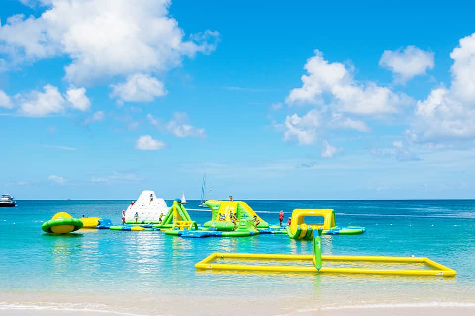 Bright inflatable water park with slide and obstacles in clear turquoise ocean water