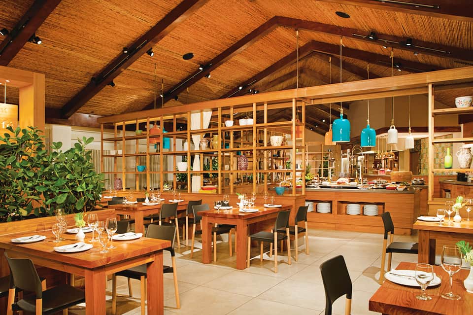 Modern restaurant interior with exposed wooden beams, dining tables, and open kitchen design