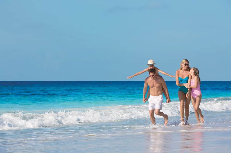 Family running into ocean waves on a sunny beach day
