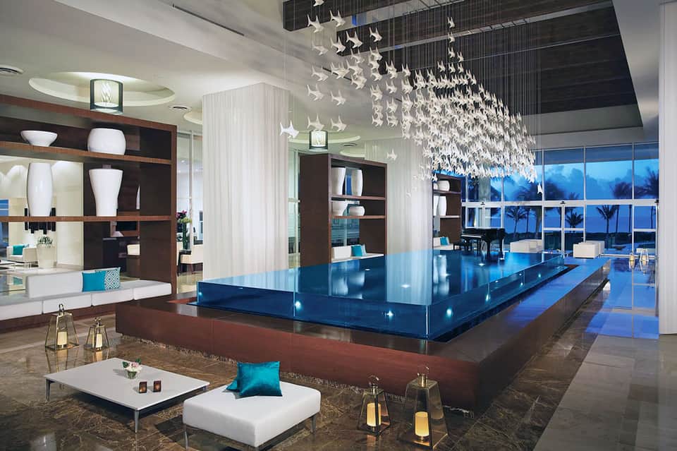 Modern hotel lobby with decorative white bird chandeliers, blue counter, and floor-to-ceiling windows