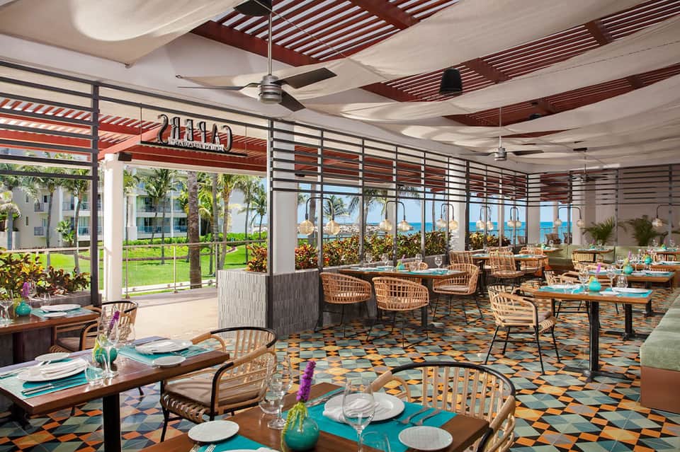 Modern dining room with colorful geometric floor, ocean views, and casual seating