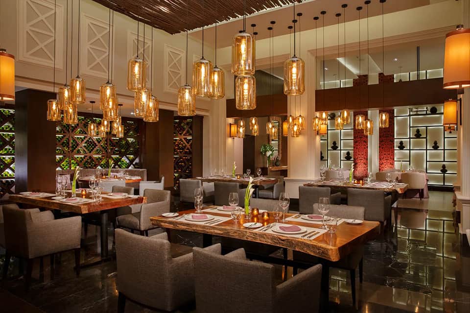 Upscale restaurant dining room with amber pendant lights and wooden tables