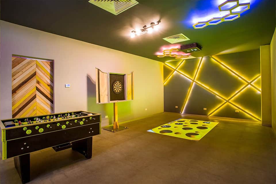 Games room with neon yellow geometric wall design, foosball table, and game equipment