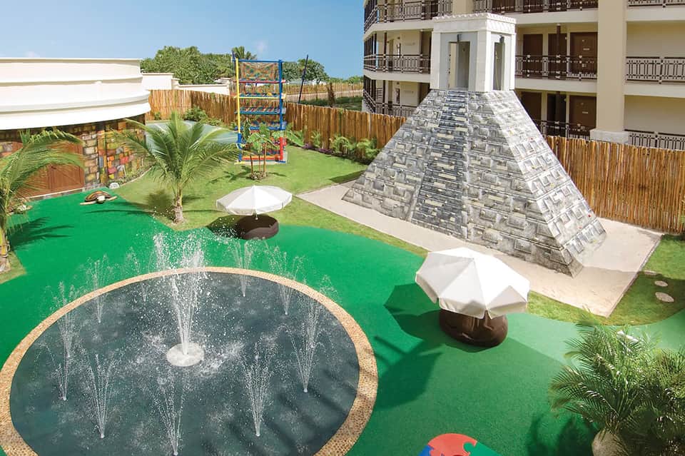 Mini golf course with colorful obstacles, fountain features, and apartment building backdrop