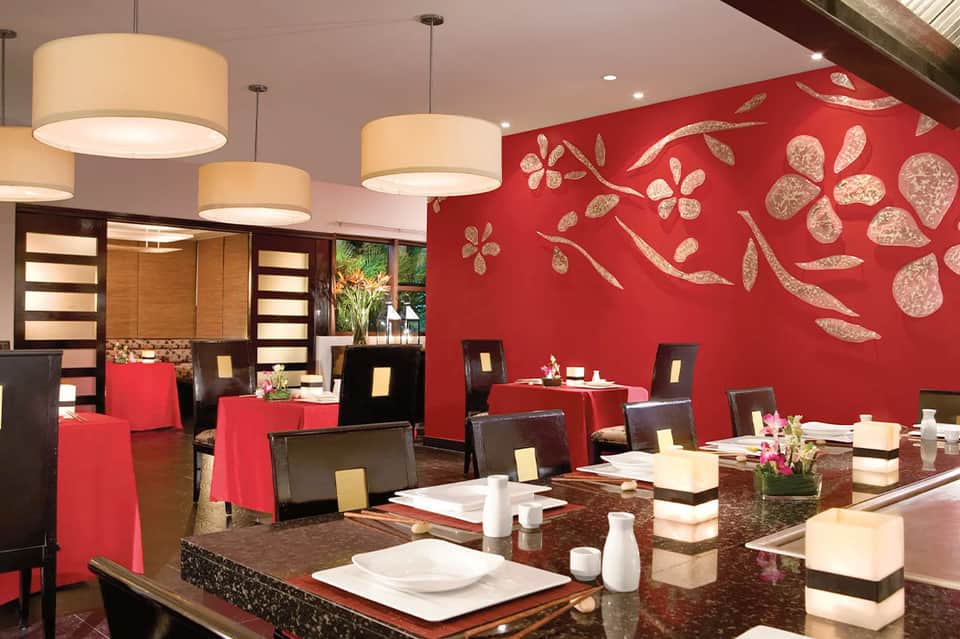 Contemporary restaurant dining room with red walls, black chairs, and gold accents