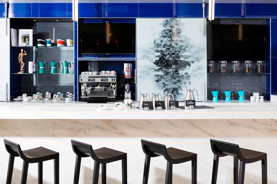 Modern coffee bar with blue cabinetry, espresso machine, and turquoise cups