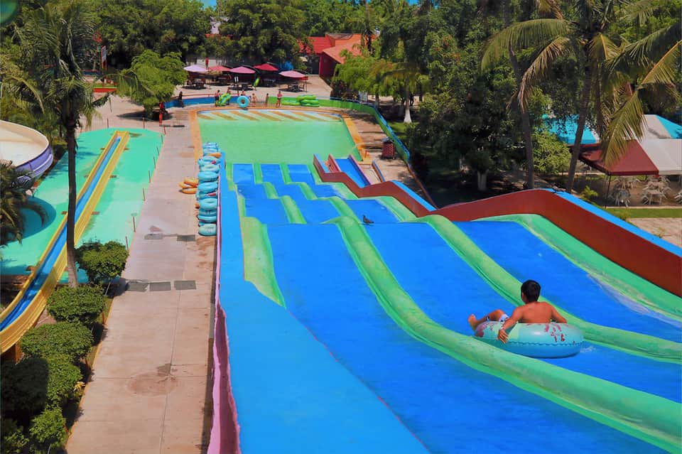 Waterpark with multiple colorful water slides surrounded by palm trees