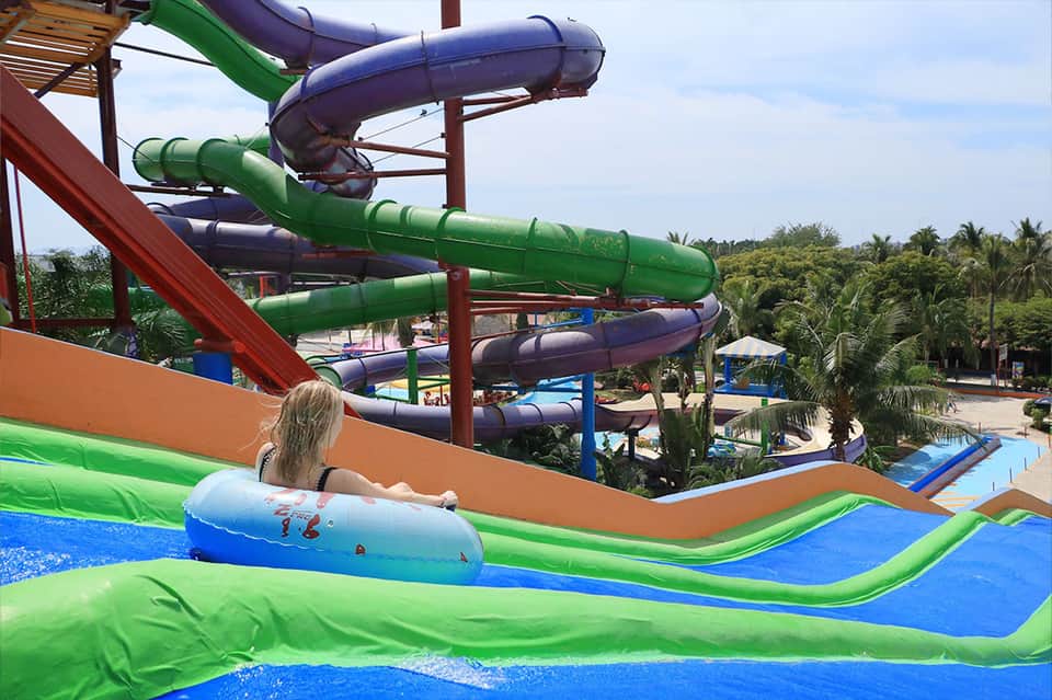 Water park with colorful slides and inflatable raft on blue landing area