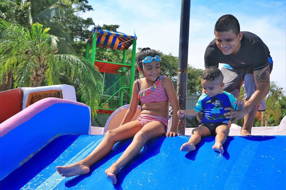Adult and children enjoying colorful water slides at resort pool area