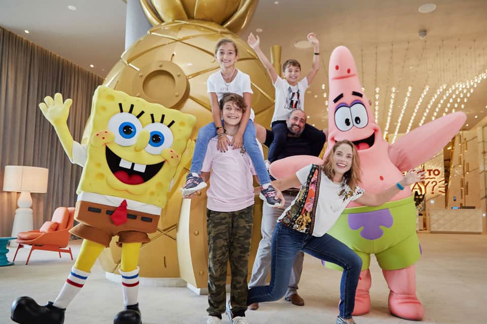 Family posing indoors with SpongeBob and Patrick character costumes during entertainment event