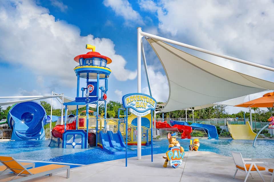 Kids water park playground with colorful slide tower, water features, and shade structures