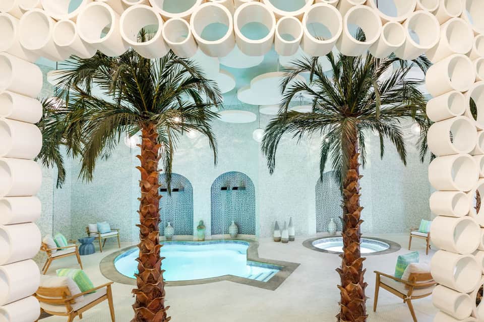 Spa interior featuring two palm trees, circular white design elements, and turquoise water feature
