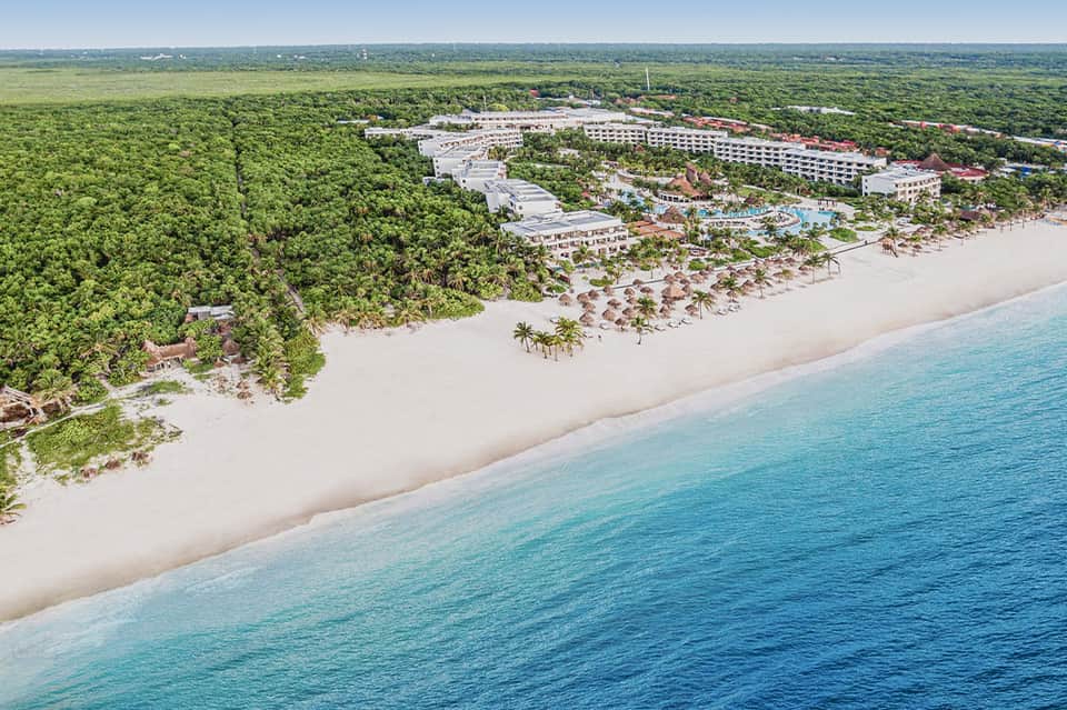 Aerial view of beachfront resort nestled between jungle and turquoise ocean