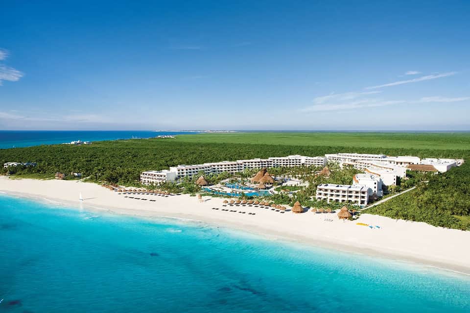 Aerial view of beachfront all-inclusive resort with pools, buildings, and pristine turquoise ocean