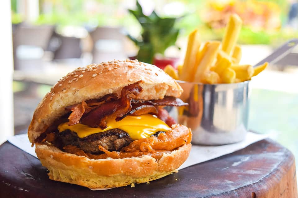 Gourmet burger with bacon and melted cheese served with golden french fries outdoors
