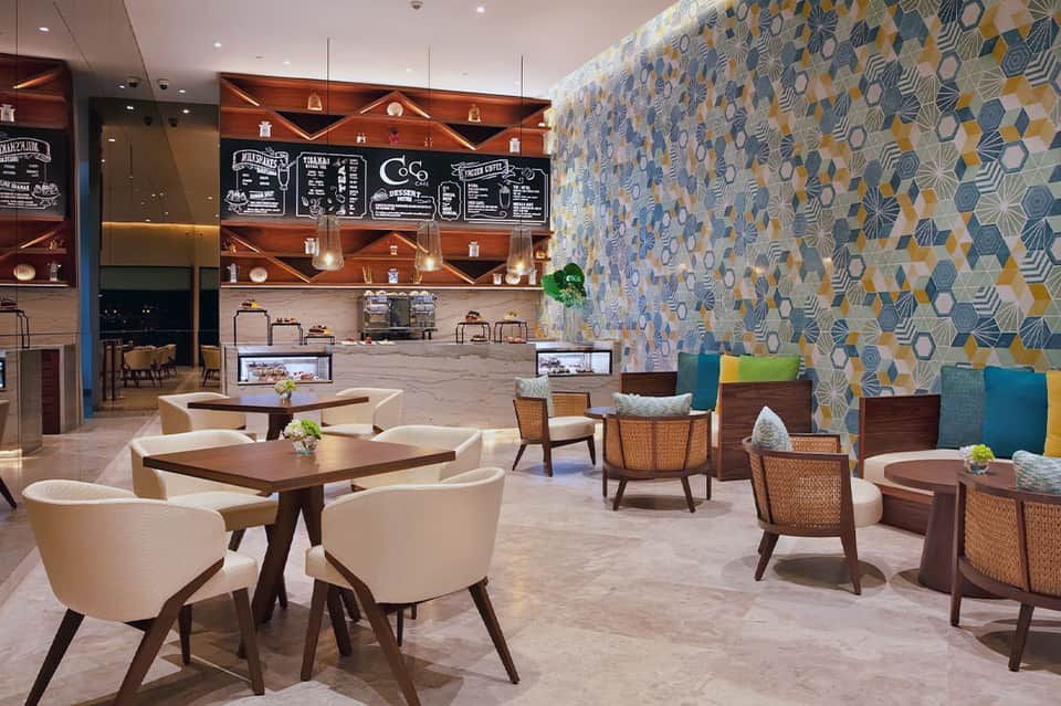 Modern hotel lobby café with patterned wall, wooden furniture, and contemporary design