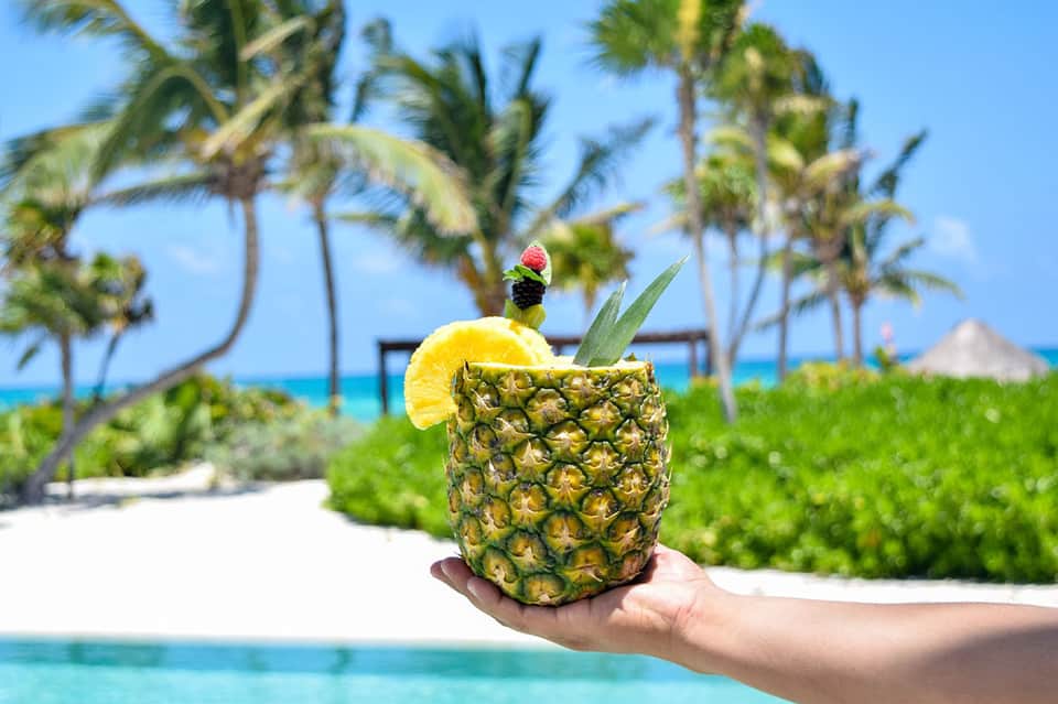 Tropical pineapple drink served beachside with palm trees and ocean