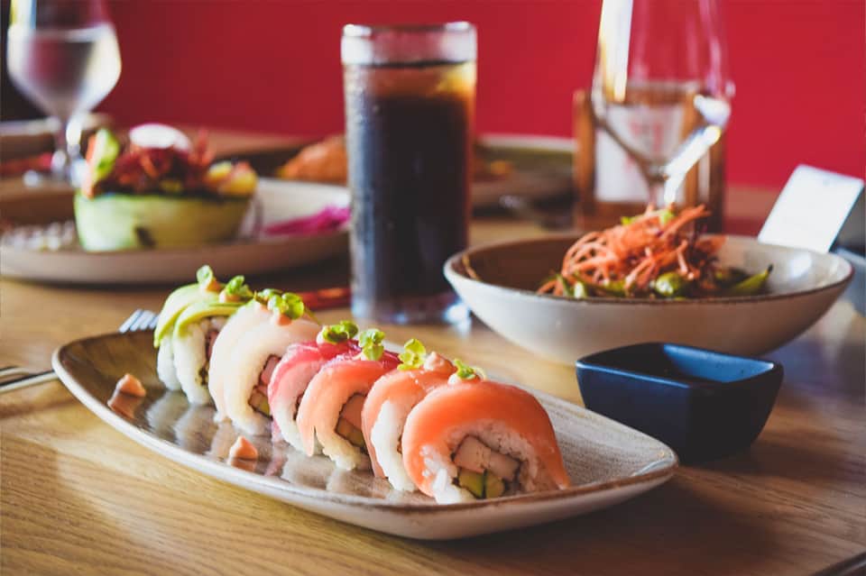 Fine dining sushi platter with cocktails and Japanese cuisine on wooden table