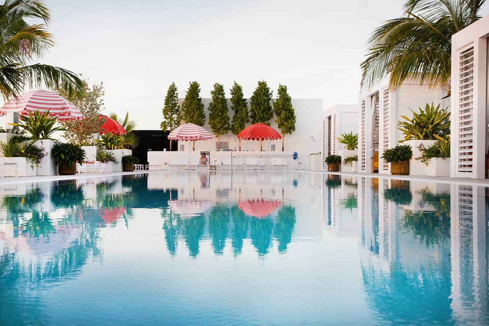 Serene resort pool with pink umbrellas, tropical landscaping, and modern architecture