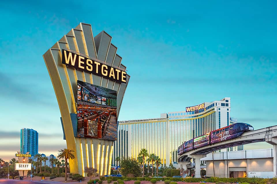 Westgate Las Vegas resort with iconic gold sign, monorail, and illuminated building at dusk